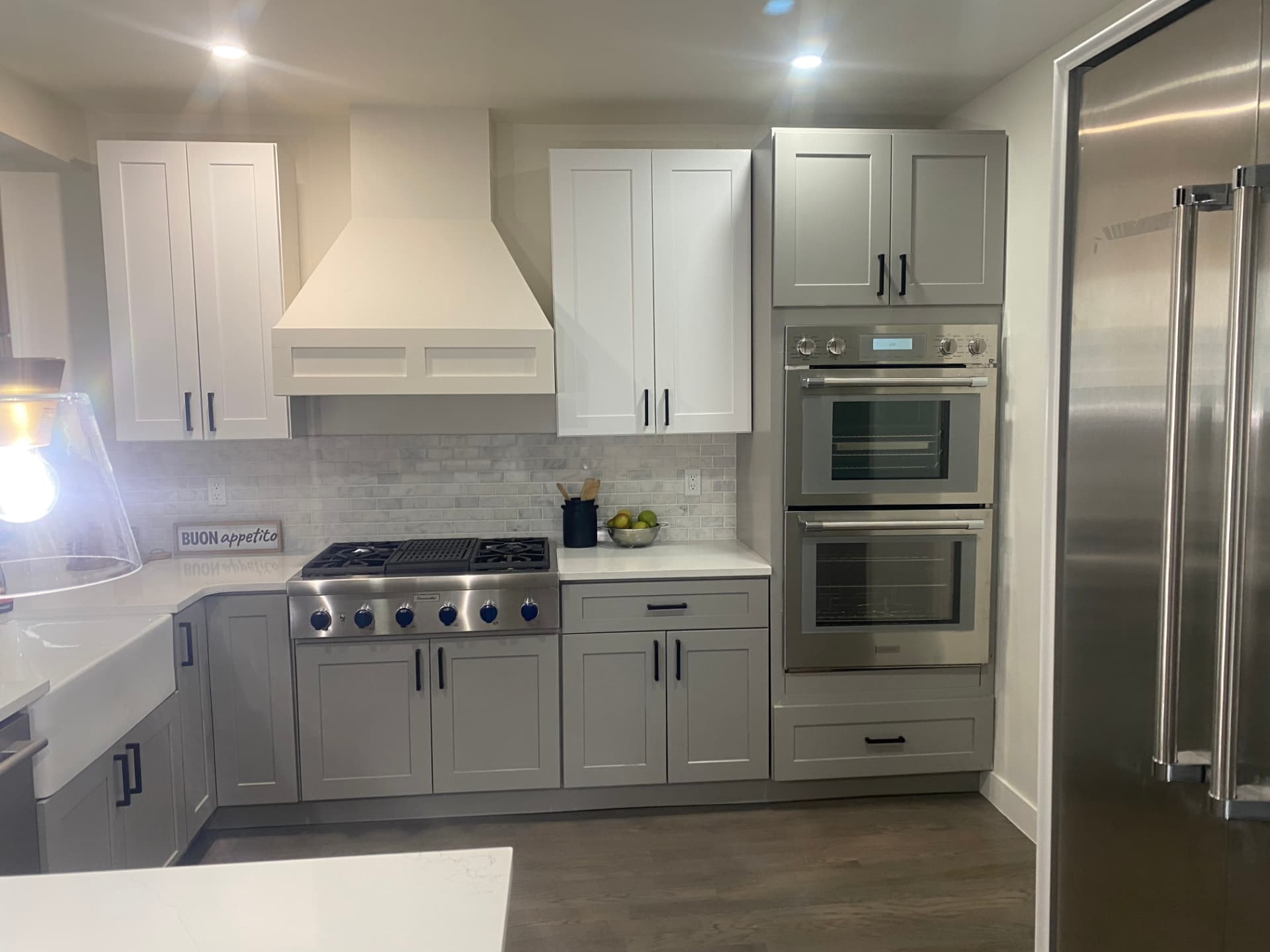Completed Denver-area kitchen remodel with gray shaker cabinets, white countertops, tile backsplash, farmhouse sink, and stainless steel appliances