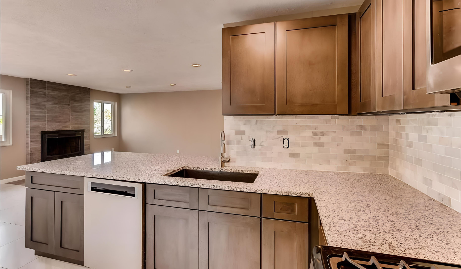 Kitchen remodeling project with two-tone wood cabinets, granite countertops, subway tile backsplash, island sink, and new flooring
