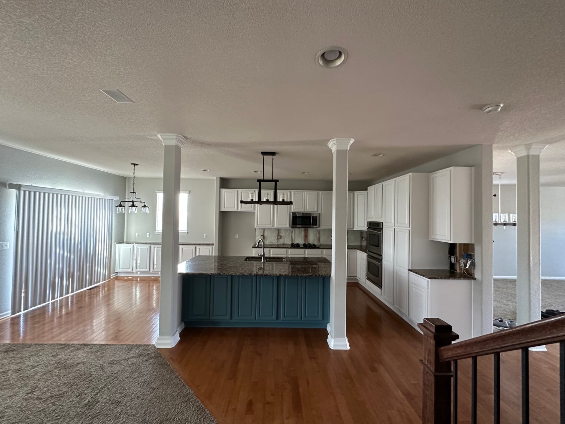 Finished kitchen after professional cabinet painting, with white perimeter cabinets and a blue painted island