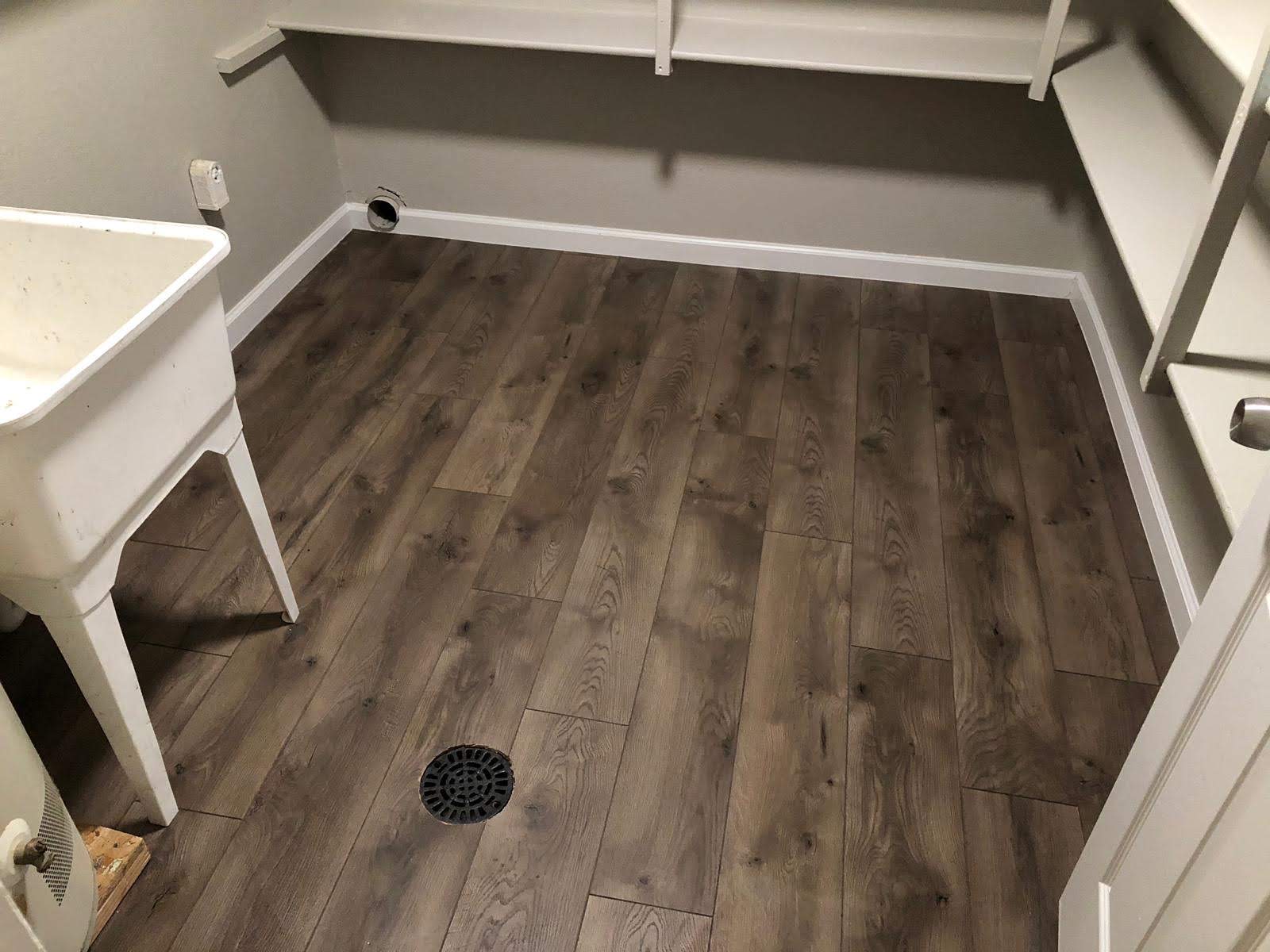 Vinyl plank flooring installed in a laundry and utility room with a floor drain and utility sink