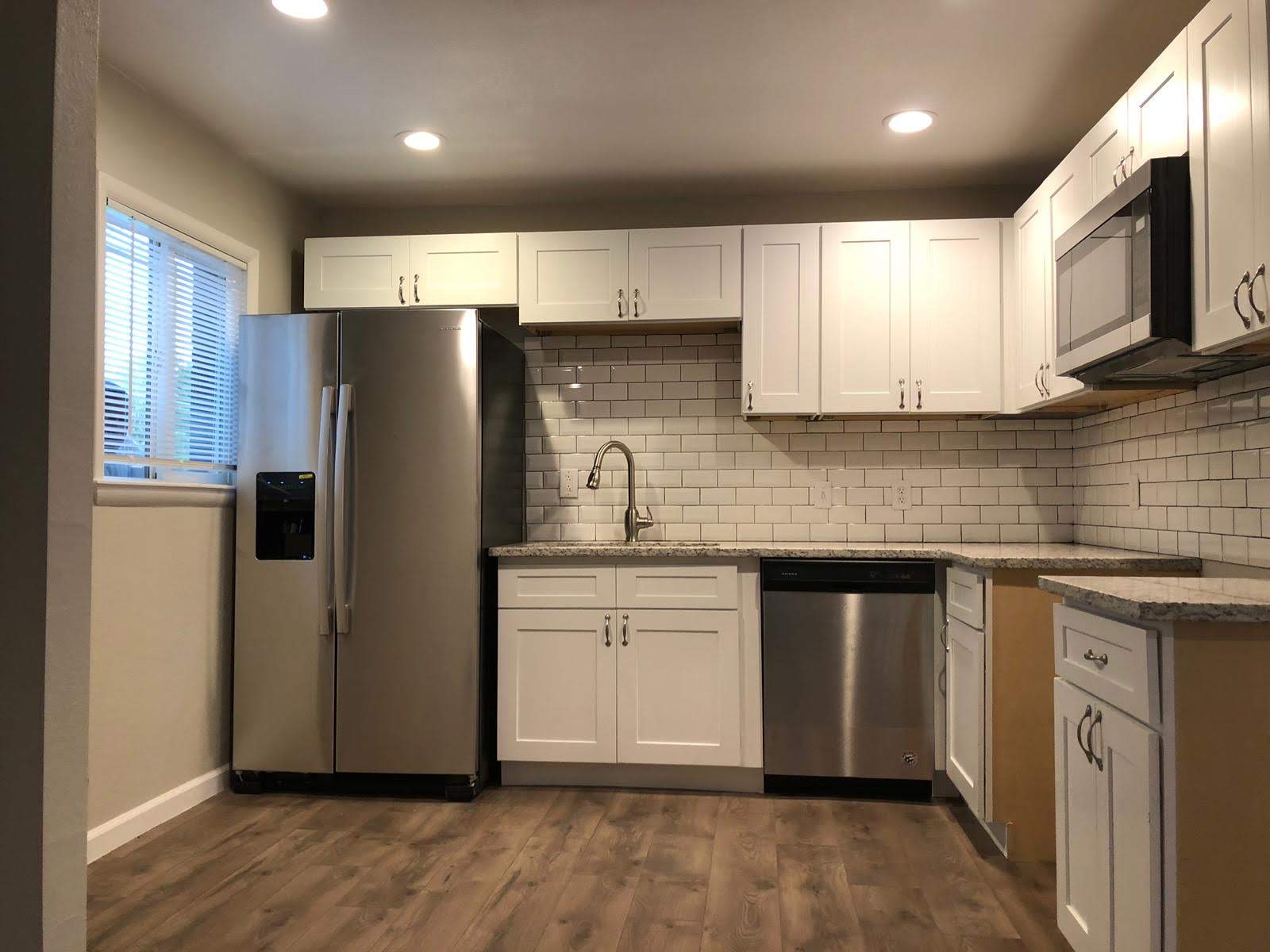 Finished basement kitchen with white cabinets, subway tile backsplash, granite counters, and stainless appliances